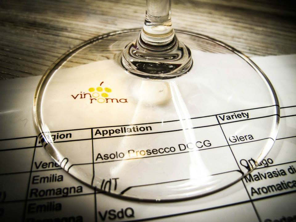 Printed material describing the wines being tasted seen through the base of a wine glass of a member during a tasting.