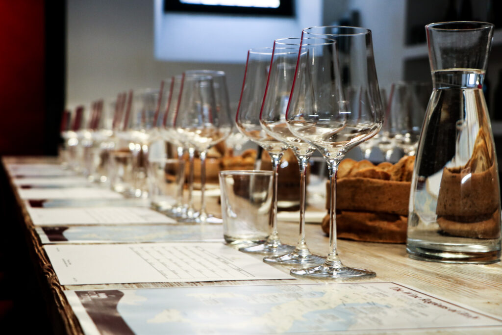 Il tavolo di degustazione di VinoRoma apparecchiato con i bicchieri, acqua, pane e dei materiali importanti per un evento speciale.