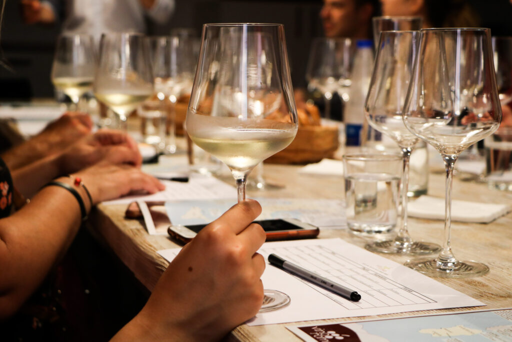 Membri tenendo un bicchiere di vino bianco mentre imparano a degustare il vino durante una degustazione.