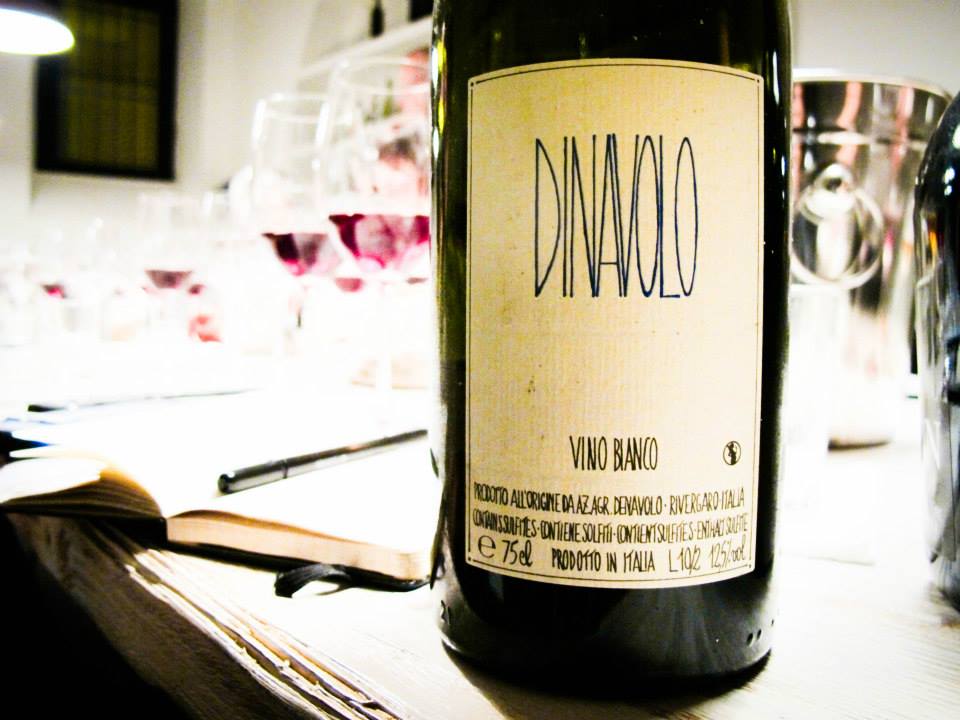 Bottle of natural wine at the VinoRoma tasting table along with open notebook and pen